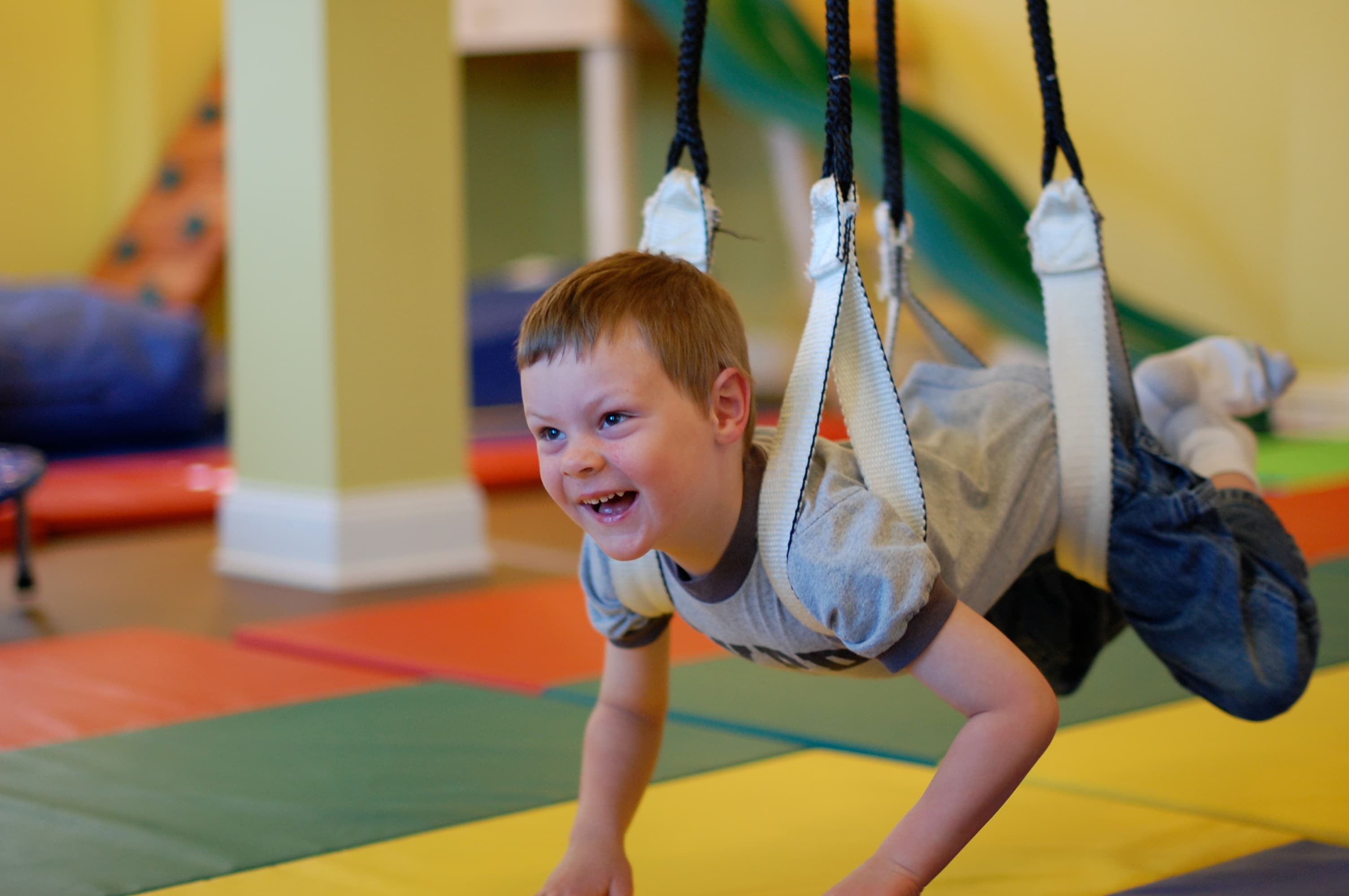 Child on sensory swing in occupational therapy gym — TILP program at KidStart Burnaby